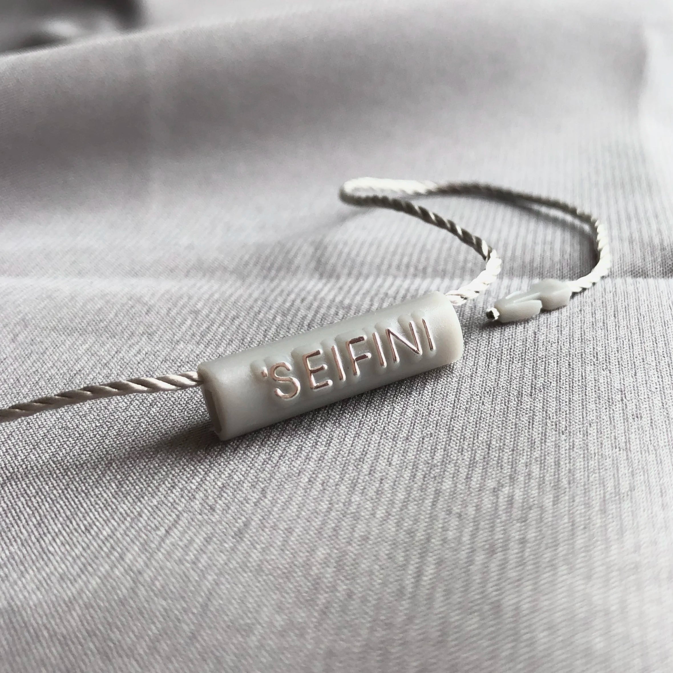 High Quality Nylon String Custom Design Brand Embossed logo Cylindrical 7*25mm Plastic Hang Tag String Label Seal Tag
