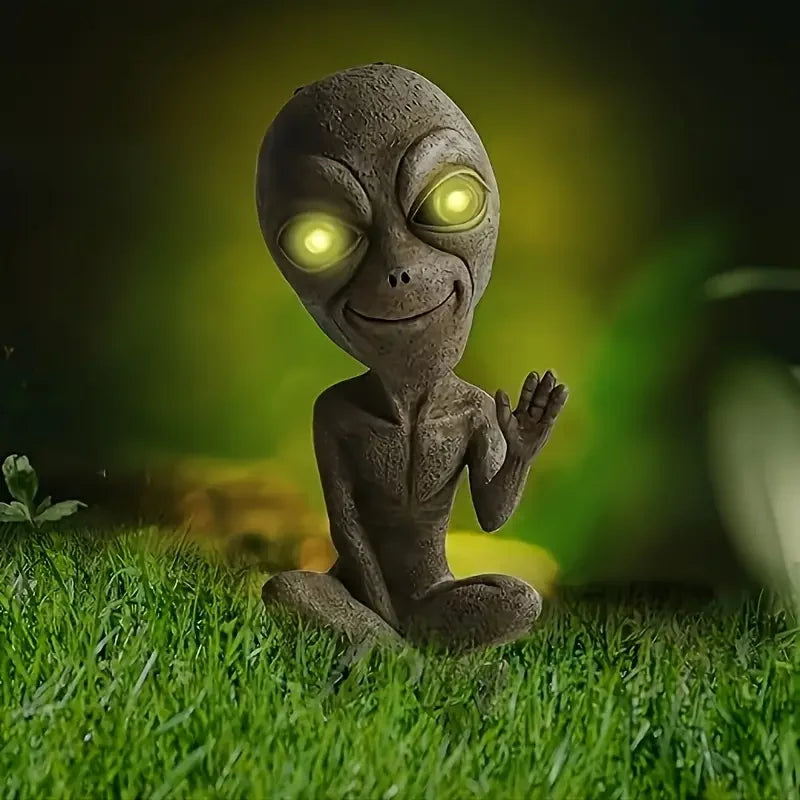 Solar Powered Friendly Alien Figurine with Glowing Green Eyes Brown Resin Sculpture Waving Hand in Garden Setting