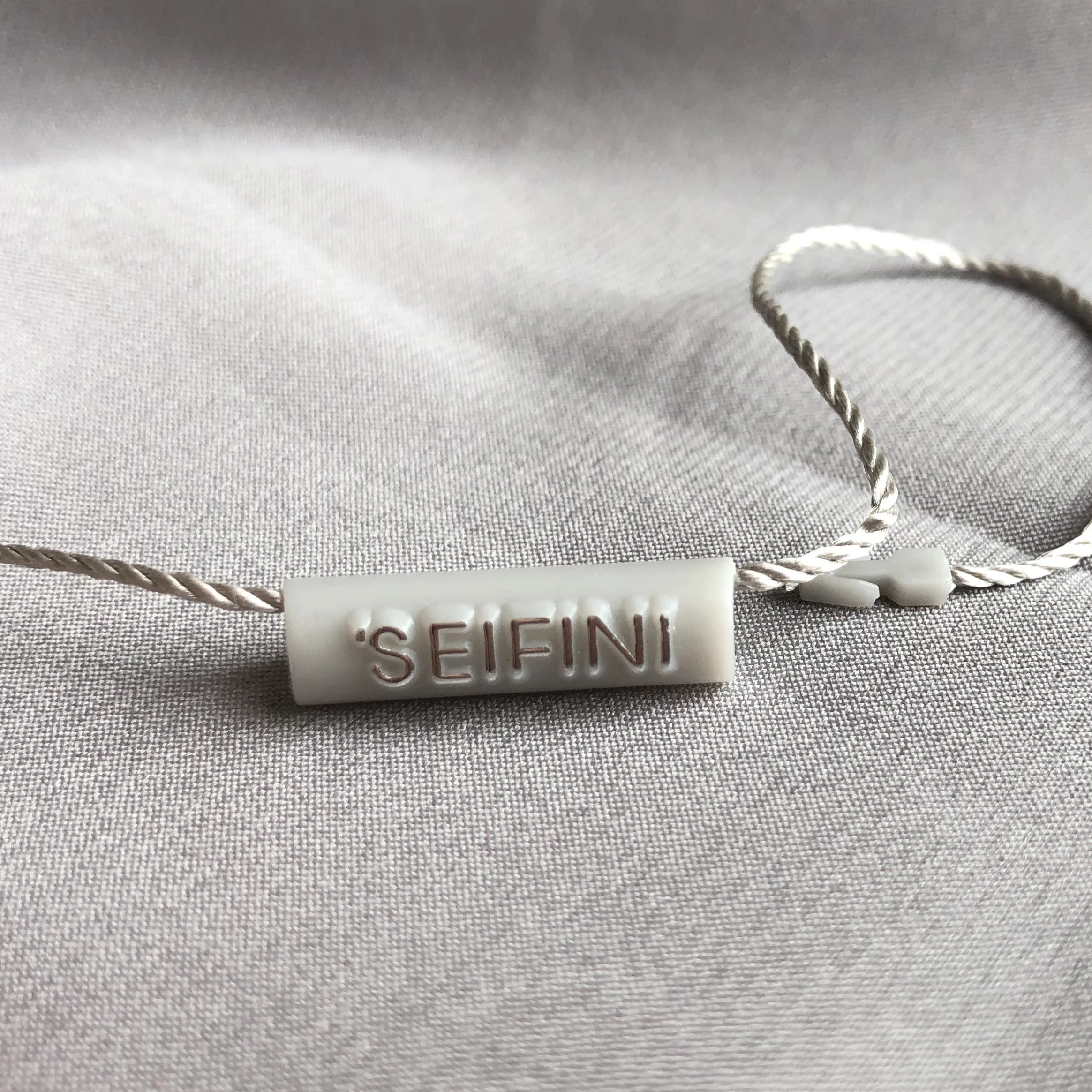 High Quality Nylon String Custom Design Brand Embossed logo Cylindrical 7*25mm Plastic Hang Tag String Label Seal Tag
